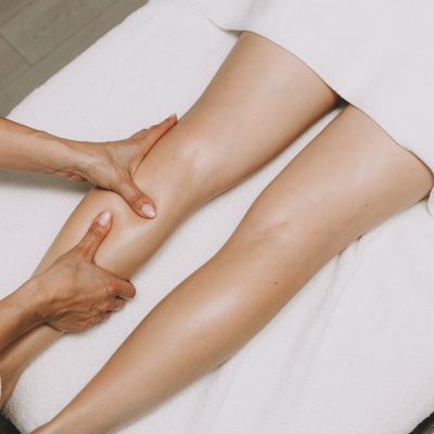 Una specialista fa un massaggio drenante alle gambe di una cliente.
